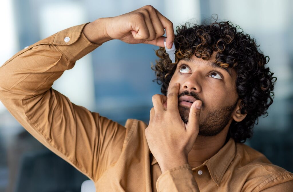 A person putting eye drops into their eye.