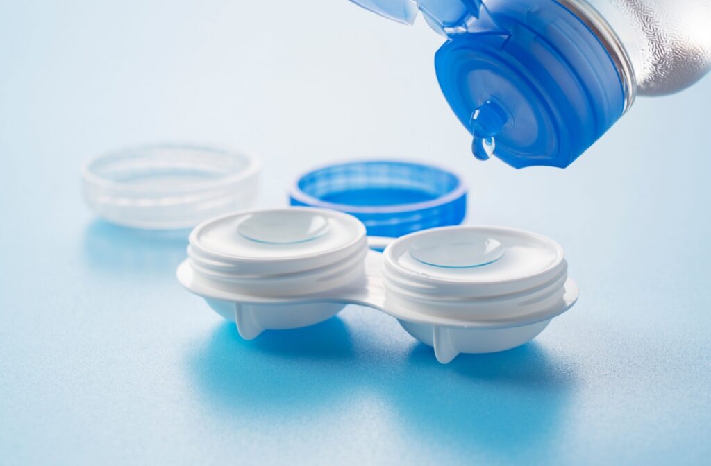 Close-up of a contact lens case being filled with solution, showing two soft contact lenses soaking inside.