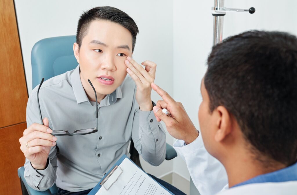 A patient points to their dry eye as they talk to an optometrist