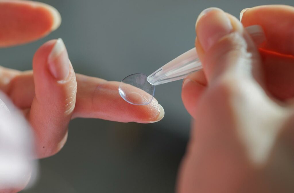 A close up of someone picking up contact lens with specialized tweezers