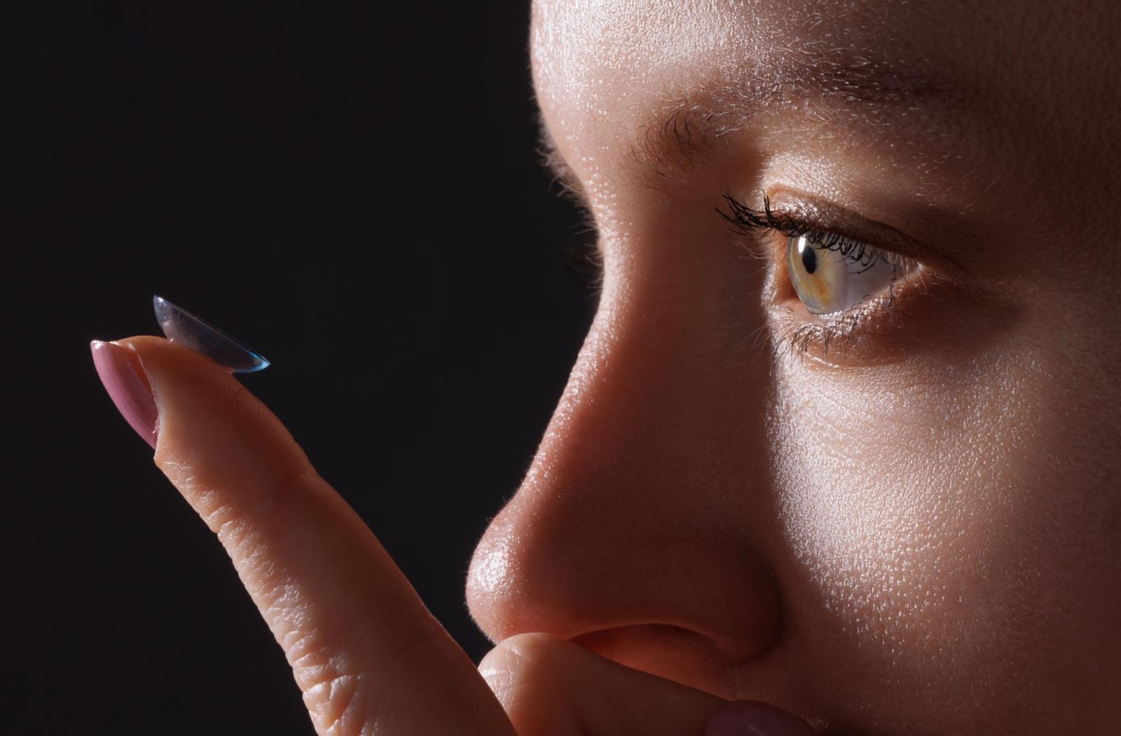 A person looking close up a contact lens on their finger